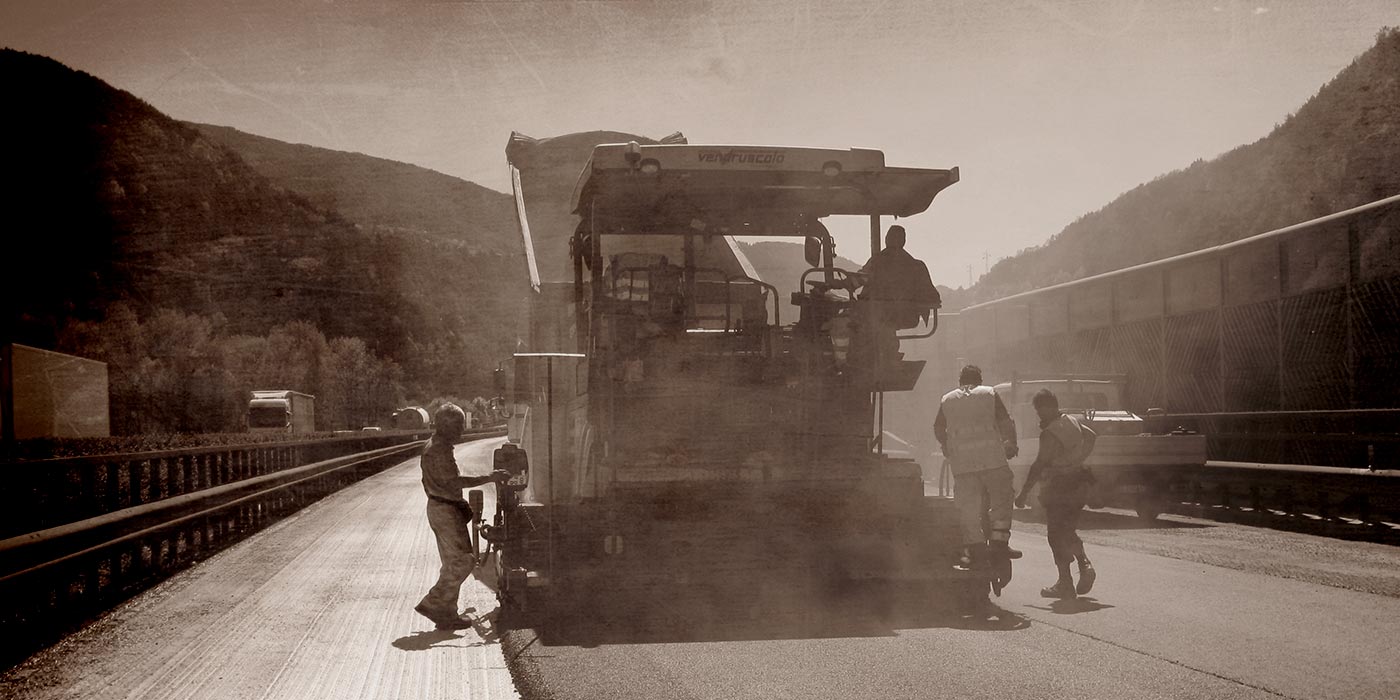 ein altes Foto in dem Arbeiter der Firma Vendruscolo auf der Autobahn Asphalt legen